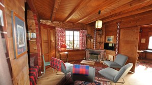 A cozy log cabin interior with a fireplace, wooden walls, and a comfortable seating area.