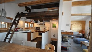 A rustic interior with exposed wooden beams, a kitchen with white cabinets, a dining area with a wooden table, and a living space with a sofa and a fireplace. - Bright and spacious Chalet Taveyanne, up to 8 people, a few meters from the Villars - Gryon - Diable (Gryon)