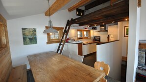 A wooden dining table with chairs, a ladder, and a kitchen in the background. - Bright and spacious Chalet Taveyanne, up to 8 people, a few meters from the Villars - Gryon - Diable (Gryon)
