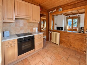 A compact kitchen with wooden cabinets, a built-in oven, and a radiator. - Chalet Tendre est la Nuit - 3 bedrooms - very pretty and cozy chalet just above the village of Gryon (Gryon)