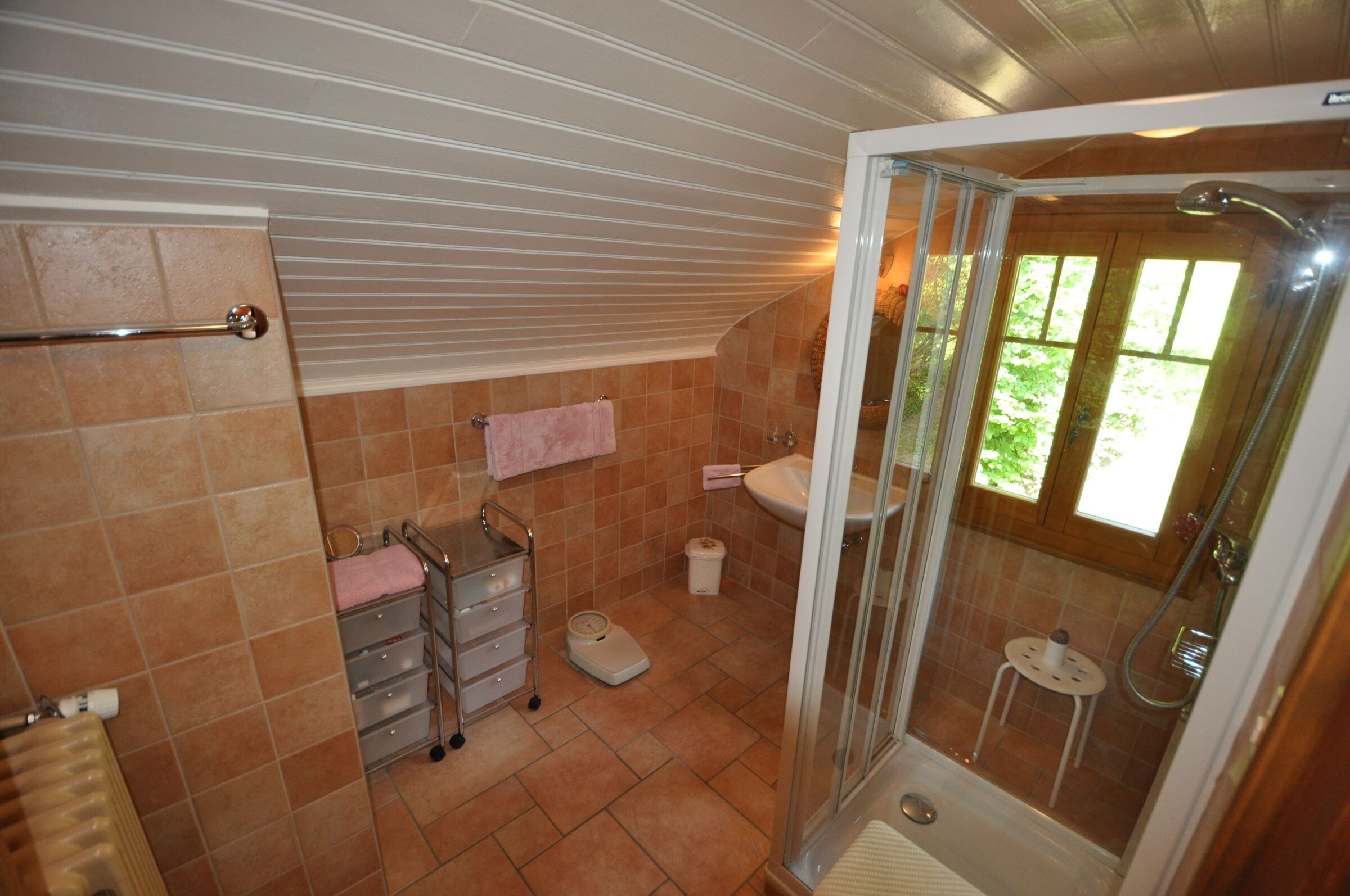 A bathroom with a shower, a sink, a toilet, and a towel rack.