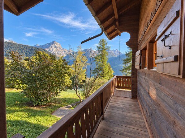 A wooden balcony with a view of mountains and trees.