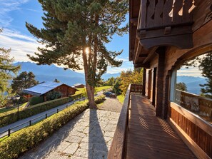 A wooden cabin with a balcony overlooking a mountainous landscape.