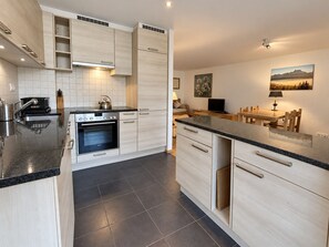 A modern kitchen with a built-in oven, a sink, and a dining area with a table and chairs. - The apartment is located 150m from the Place de la Barboleuse in Gryon and is close to all amenities (Gryon)