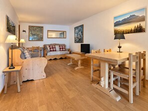 A cozy living room with a wooden sofa, a dining table with chairs, and artwork on the walls. - The apartment is located 150m from the Place de la Barboleuse in Gryon and is close to all amenities (Gryon)
