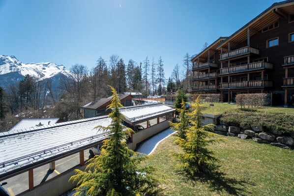 A lodge with a wooden exterior, a covered bridge, and a mountain backdrop.