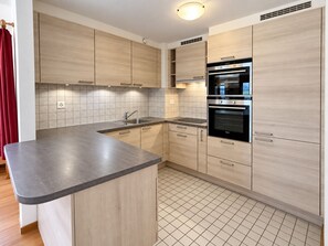 Een moderne keuken met lichte houten kastjes, een roestvrijstalen spoelbak en een dubbele oven.