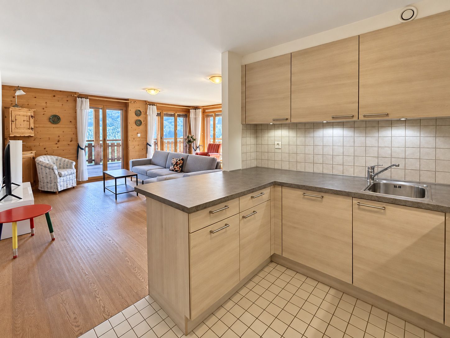 Une cuisine moderne avec des meubles en bois, un grand îlot central et une vue sur un balcon.