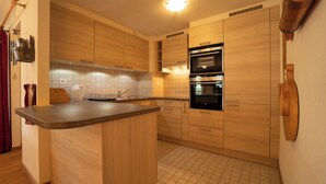Una cocina moderna con armarios de madera, encimera de acero inoxidable y hornos empotrados.