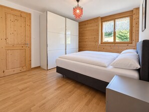Une chambre à coucher comprenant un lit, une armoire, une commode et une fenêtre donnant sur un paysage verdoyant.