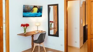 A bedroom with a bed, a desk, a chair, a TV, and a mirror. - Relais CuoreNapoletano (Naples)