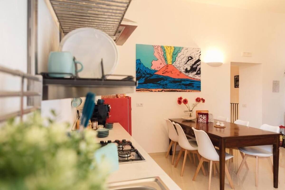 Cocina moderna con comedor, un cuadro en la pared y un refrigerador rojo.
