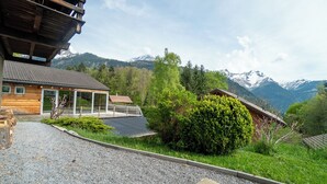Una cabaña de madera con un porche cubierto y vistas a montañas nevadas.