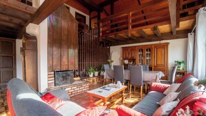Una sala de estar acogedora con chimenea, vigas de madera, un conjunto de sofás y una zona de comedor.