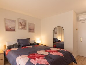 Ein Schlafzimmer mit Bett, Nachttischen, einem Spiegel und Wandbildern.