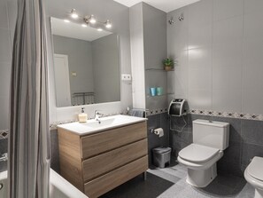 Ein modernes Badezimmer mit einem Holzkosmetikschrank, einem großen Spiegel, einer Dusche und einer Toilette.