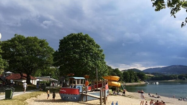 Una playa con un parque infantil, un tobogán acuático y una zona de arena con gente.