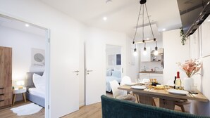 Una habitación moderna y luminosa con una mesa de comedor de madera, un banco tapizado de verde y una cama blanca con cabecera de madera.