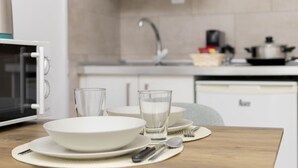 Una cocina con gabinetes blancos, un microondas, un lavamanos y una estufa.