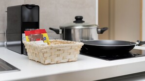 Una cocina con estufa, olla, cesta con alimentos y cafetera.
