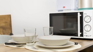 Un microondas sobre una encimera de madera con un plato, un bol y un vaso.
