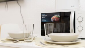 A dining area with a microwave, two bowls, and two glasses on a table. - Classy IX - Ferga Suites (Madrid)