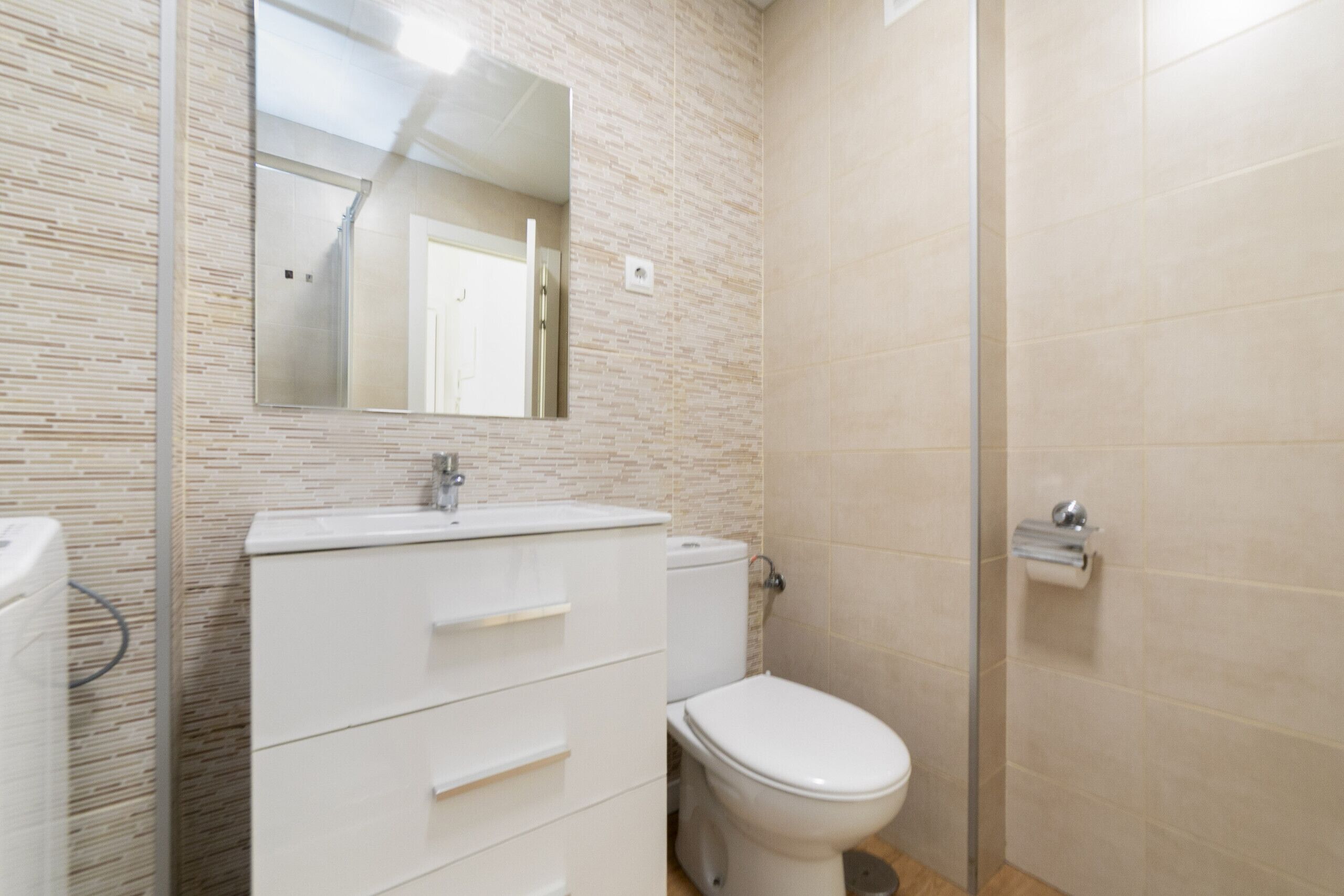 A bathroom with a white sink, mirror, and toilet.