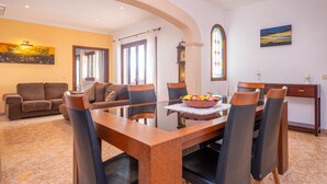 A dining area with a wooden table and chairs, a stained glass window, and a painting on the wall.