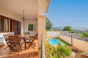 A terrace with a dining table and chairs, a small pool, and a view of the surrounding landscape.