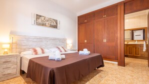 A hotel room with a large bed, wooden wardrobe, and a bathroom visible through an open door.