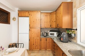 A kitchen with wooden cabinets, a white refrigerator, a microwave, a coffee maker, and a sink. - Casa Algodon in Chiclana de la Frontera (Chiclana de la Frontera)