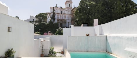 A rooftop pool with a view of a historic church and surrounding greenery.