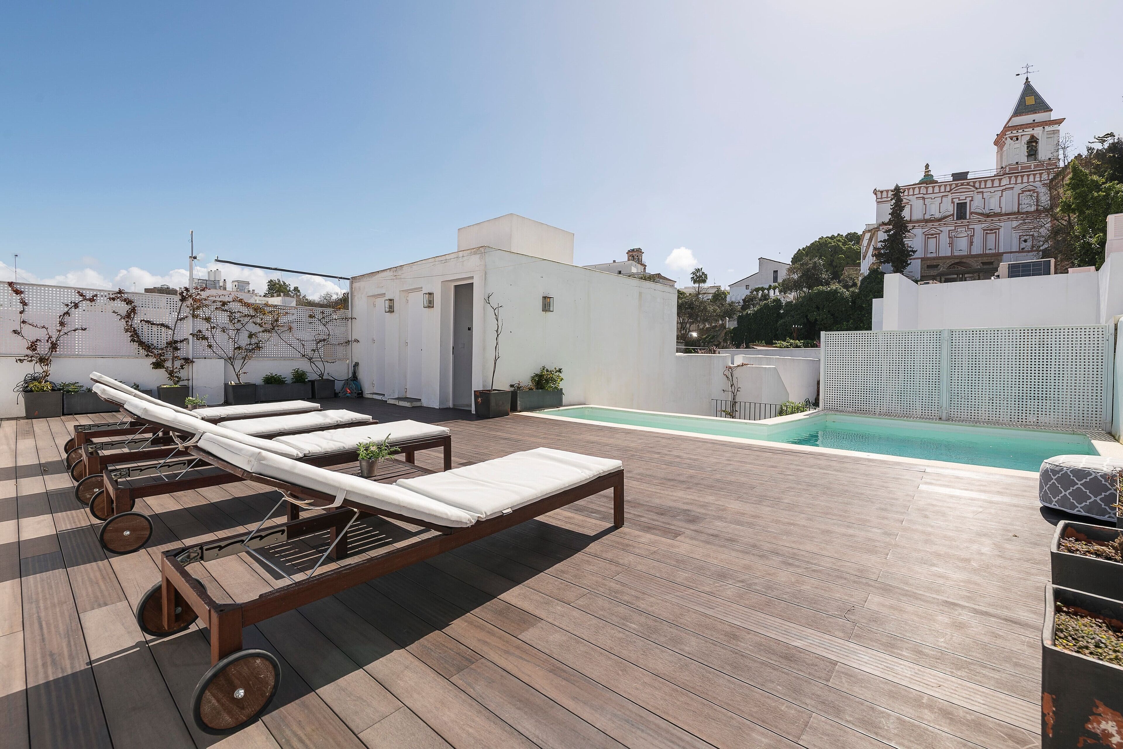 A rooftop pool area with lounge chairs and a view of a historic building in the background.