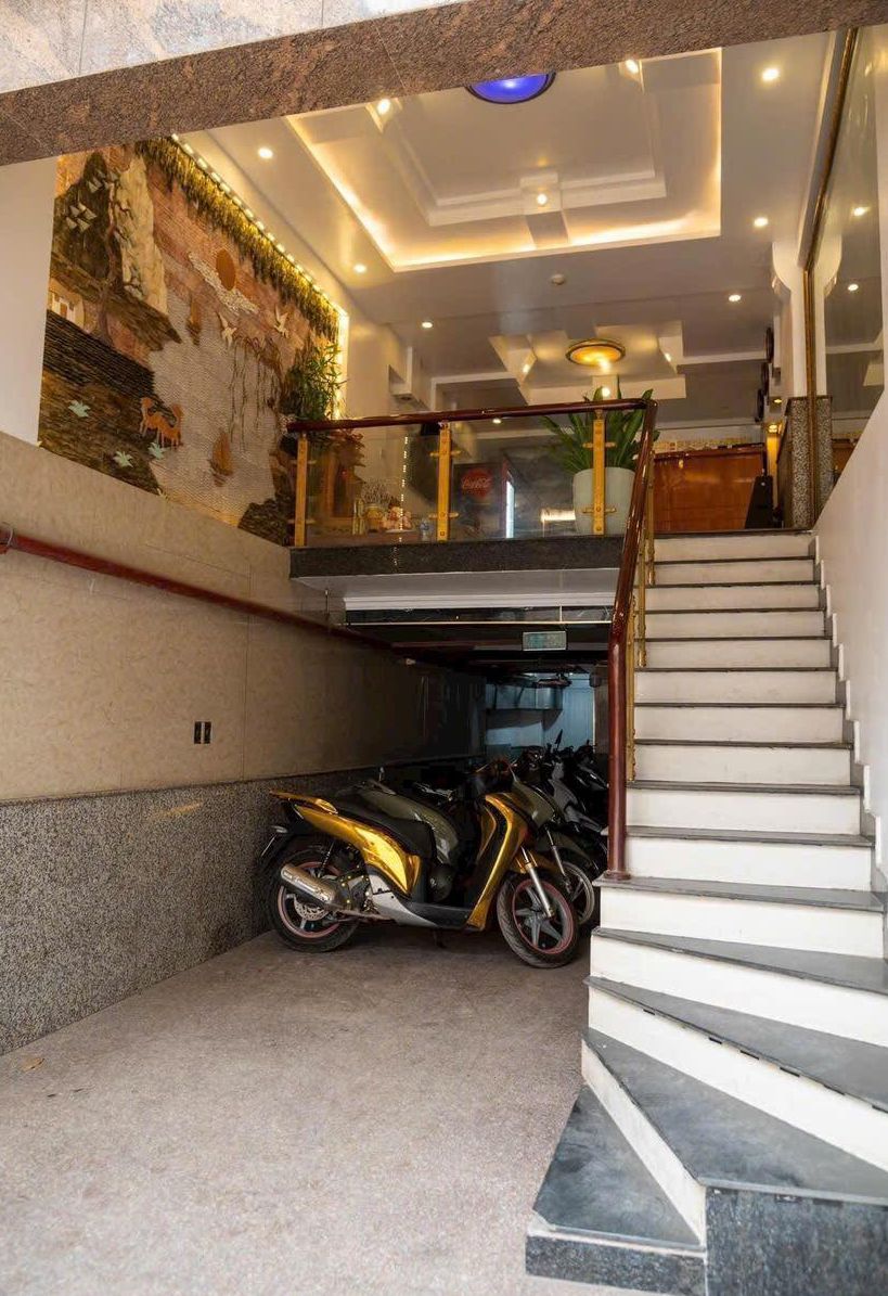 Un interior moderno con una escalera que sube a un segundo piso, un mural en la pared y una motocicleta estacionada en un rincón.