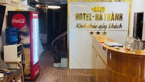 Un espace d’accueil d’hôtel comprenant un réfrigérateur Coca-Cola, un distributeur d’eau et un comptoir de réception.