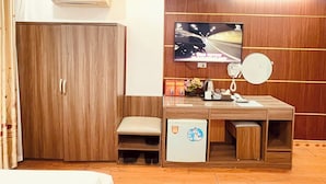 Une chambre d’hôtel équipée d’un lit, d’un bureau, d’une télévision, d’un téléphone et d’un appareil de climatisation.