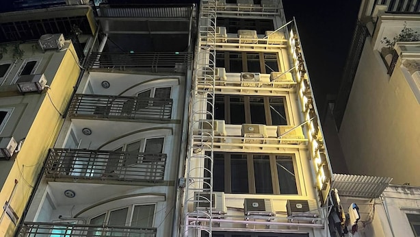 Un immeuble à plusieurs étages, avec une enseigne indiquant « HÔTEL HA THANH » et, en dessous, une autre enseigne indiquant « SALON DE THÉ ».