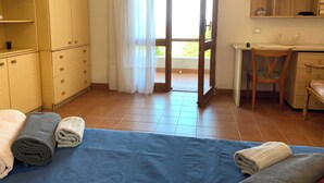 Un dormitorio con cama, escritorio, silla y armario.