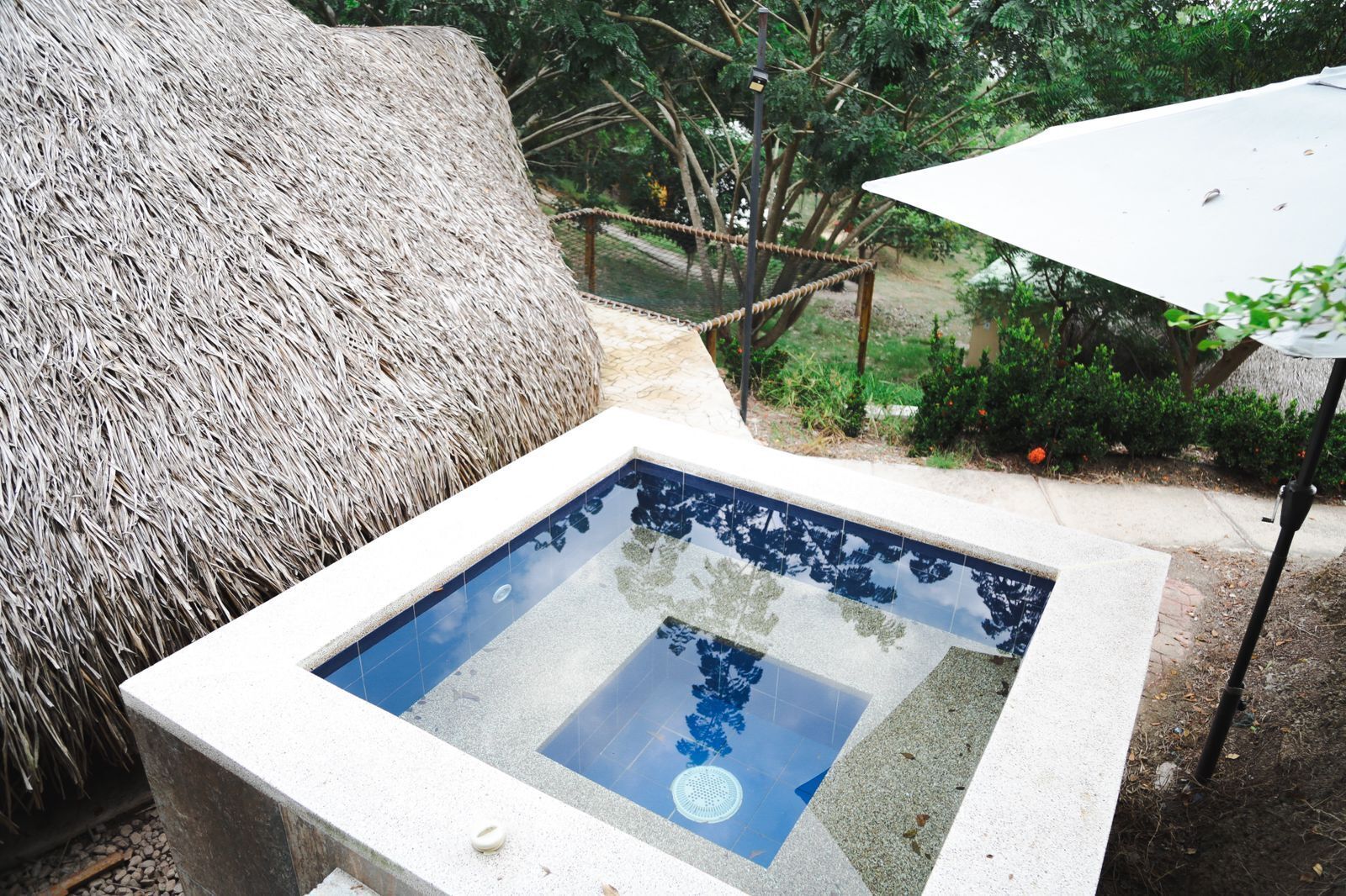 Uma piscina retangular com água azul límpida, rodeada por uma borda de concreto.