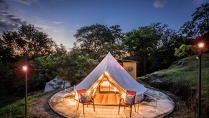 A tent with a circular seating area and a small building nearby. - Mangoo Glamping (Melgar)