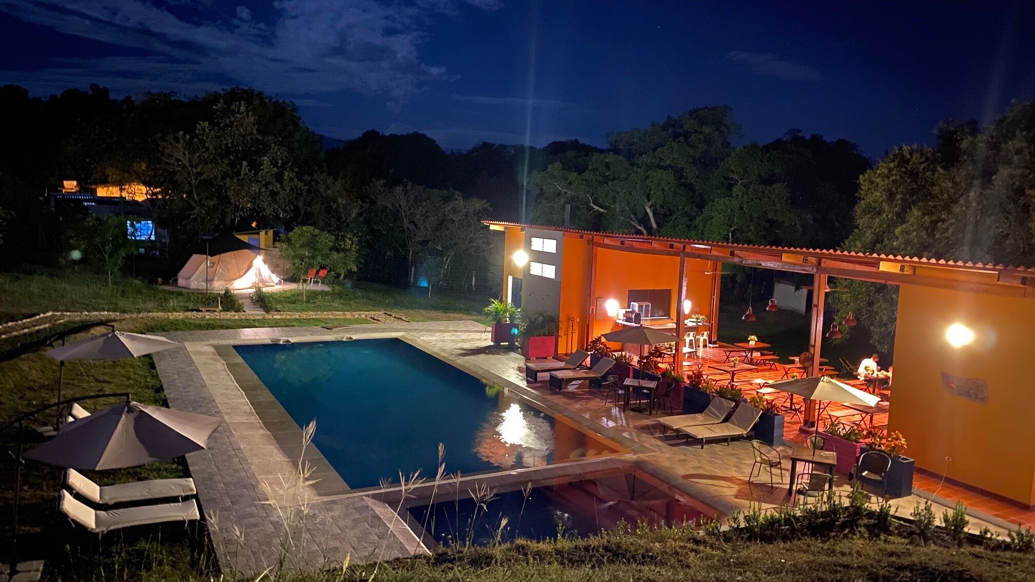 Una piscina con sillas de descanso y un patio cubierto.