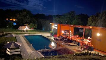 Una piscina con sillas de descanso y un patio cubierto.