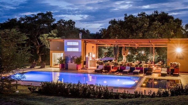 A modern outdoor pool area with lounge chairs and a covered seating area. - Mangoo Glamping (Melgar)