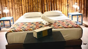 A bed with a patterned blanket, a bedside table, and a lamp. - Mangoo Glamping (Melgar)