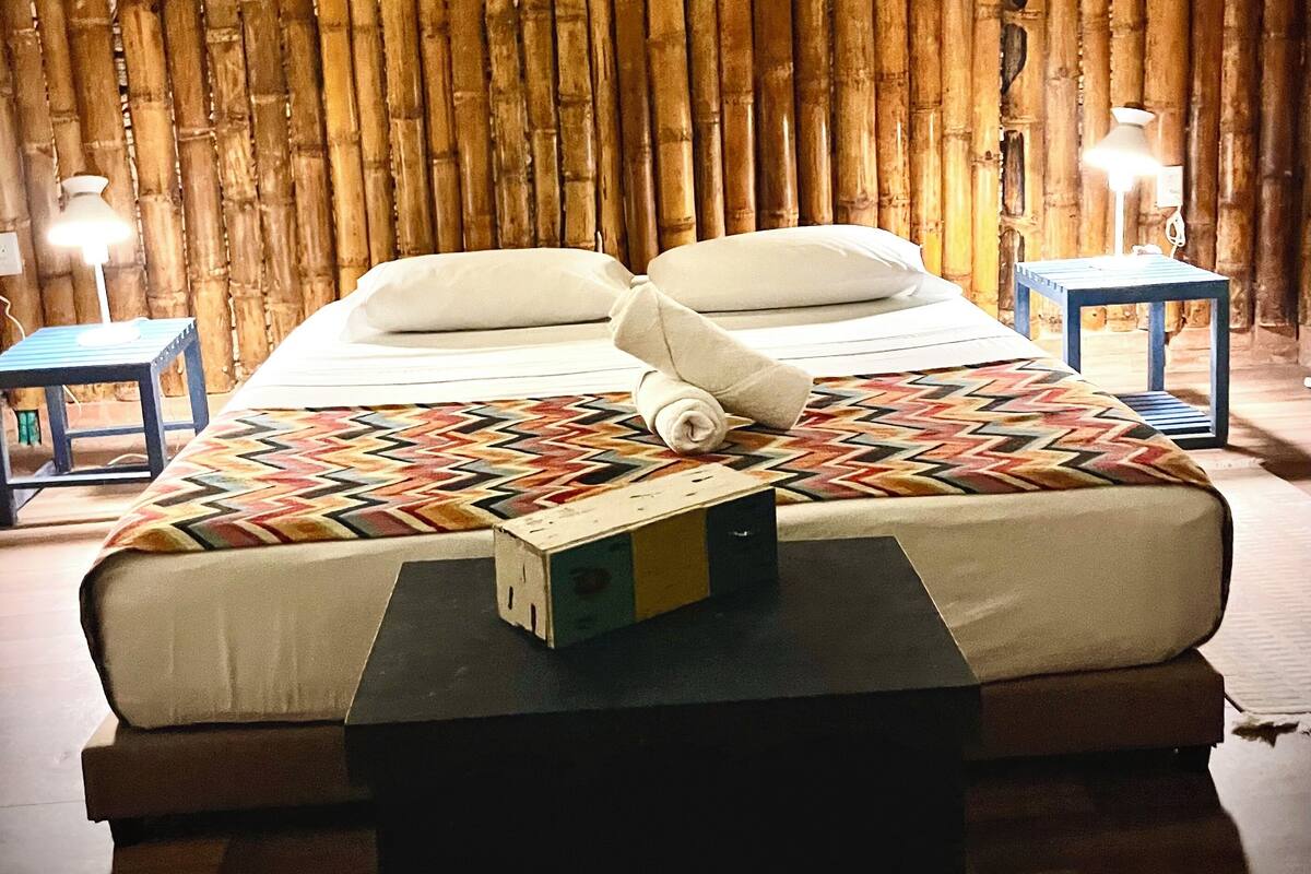 Una cama con un edredón estampado, una mesita de noche y una lámpara.
