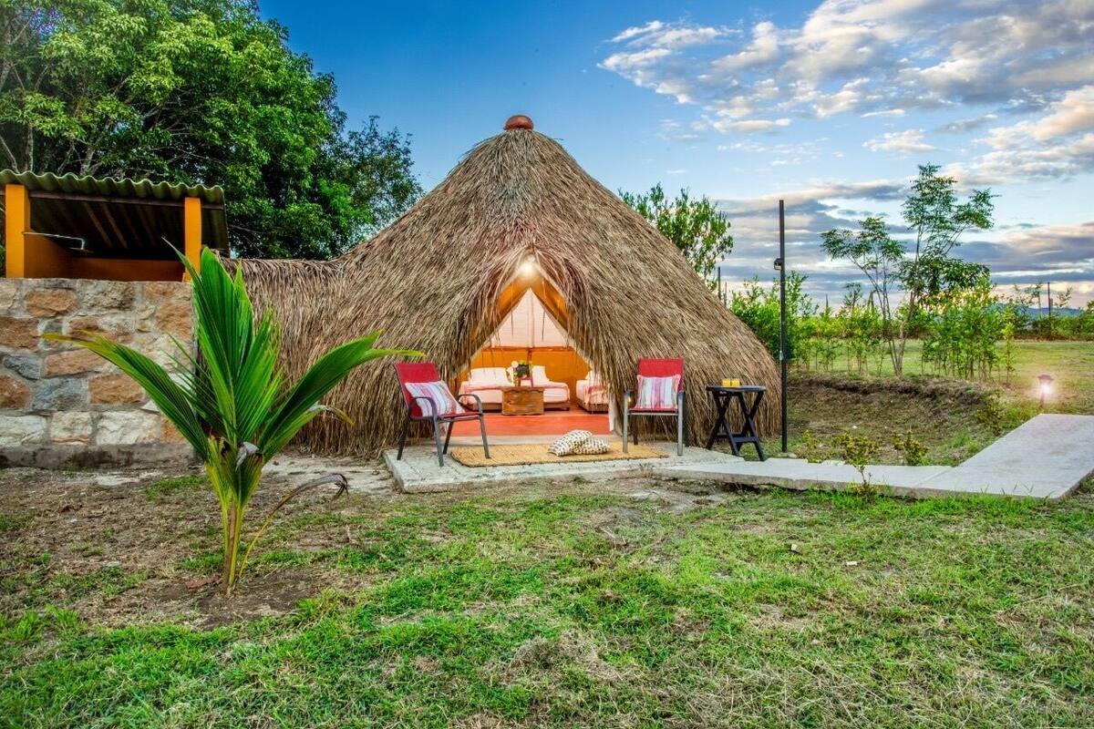Una cabaña con techo de paja y un interior acogedor, paredes de piedra y un pequeño jardín.