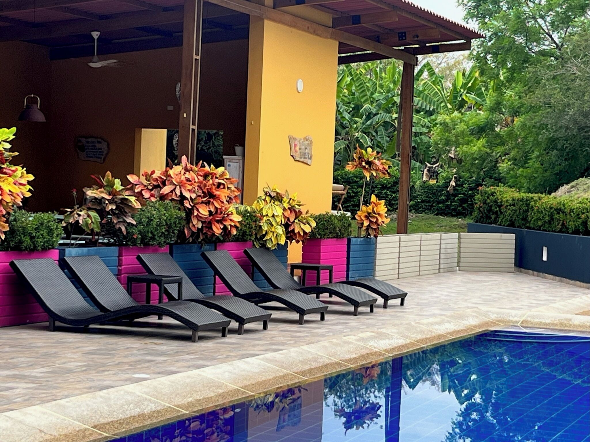 Un espace aménagé au bord de la piscine, avec des chaises longues, une terrasse carrelée et une piscine.