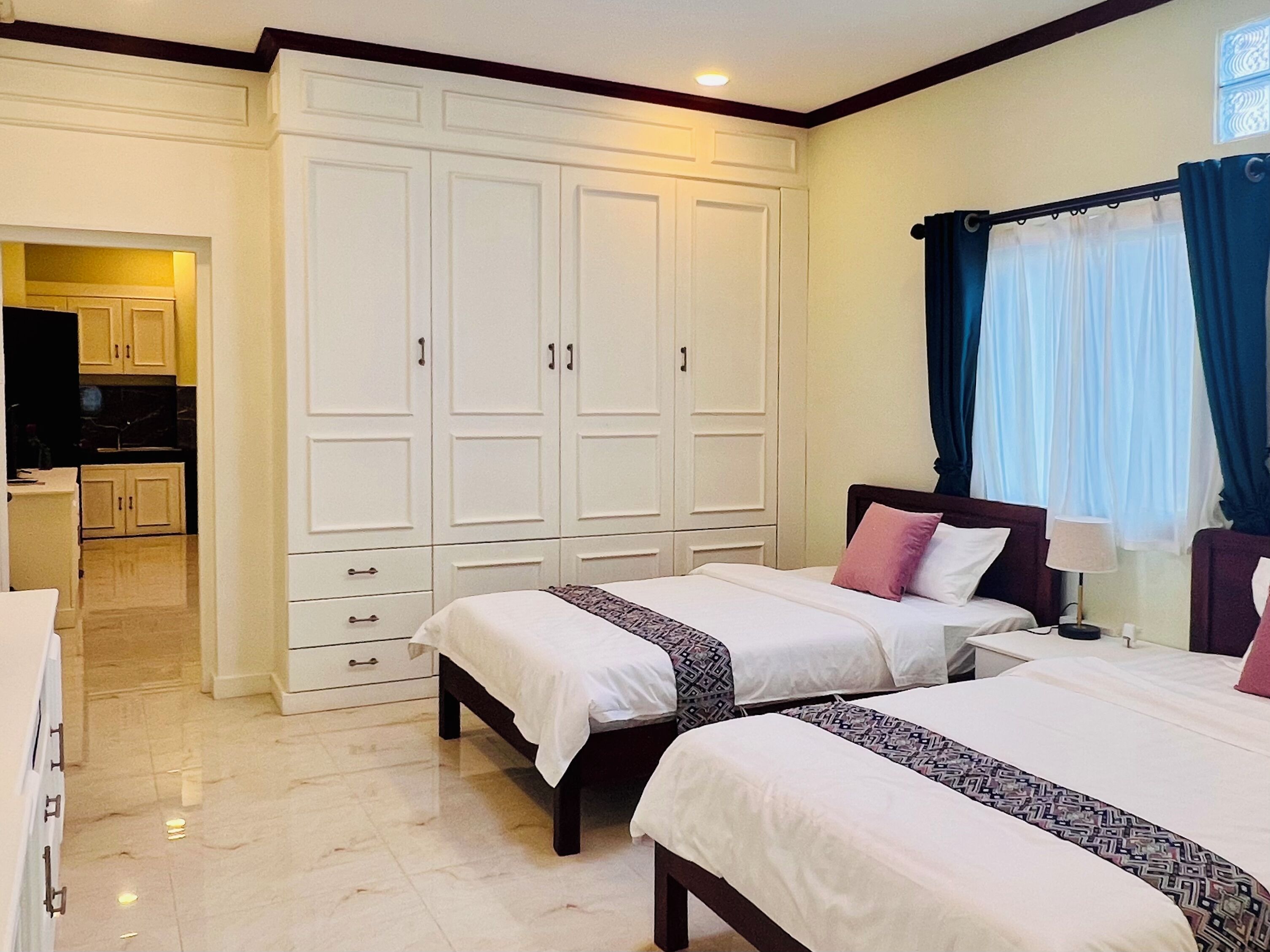 Une chambre d’hôtel avec deux lits, une armoire, une salle de bain et une kitchenette.