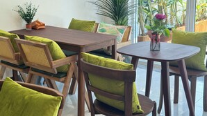 A dining area with wooden tables and chairs, green cushions, and potted plants. - Vanida Hotel (Vientiane)