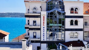 Ein Hotel namens "HOTEL BAVARIA" mit moderner Architektur, Balkonen und Meerblick.